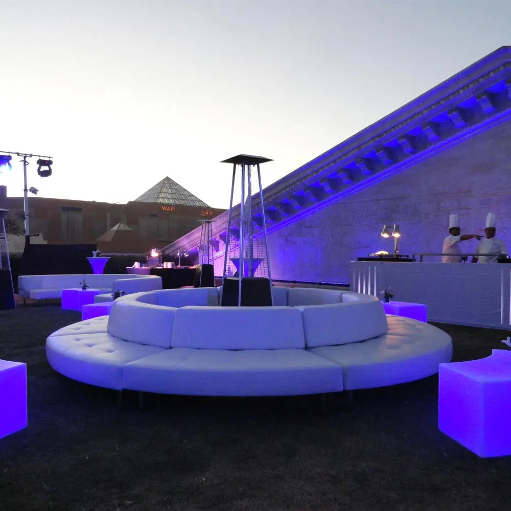 Corporate event styling featuring circular, modular, lounge seating, LED lighting, and an outdoor bar setup at dusk.