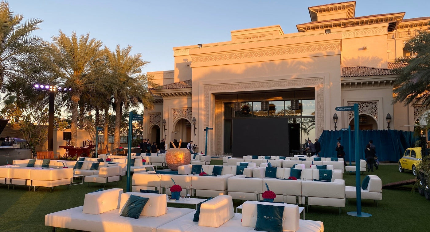 Event seating arrangement for an outdoor venue with modern white sofas and tables set up in front of a stage