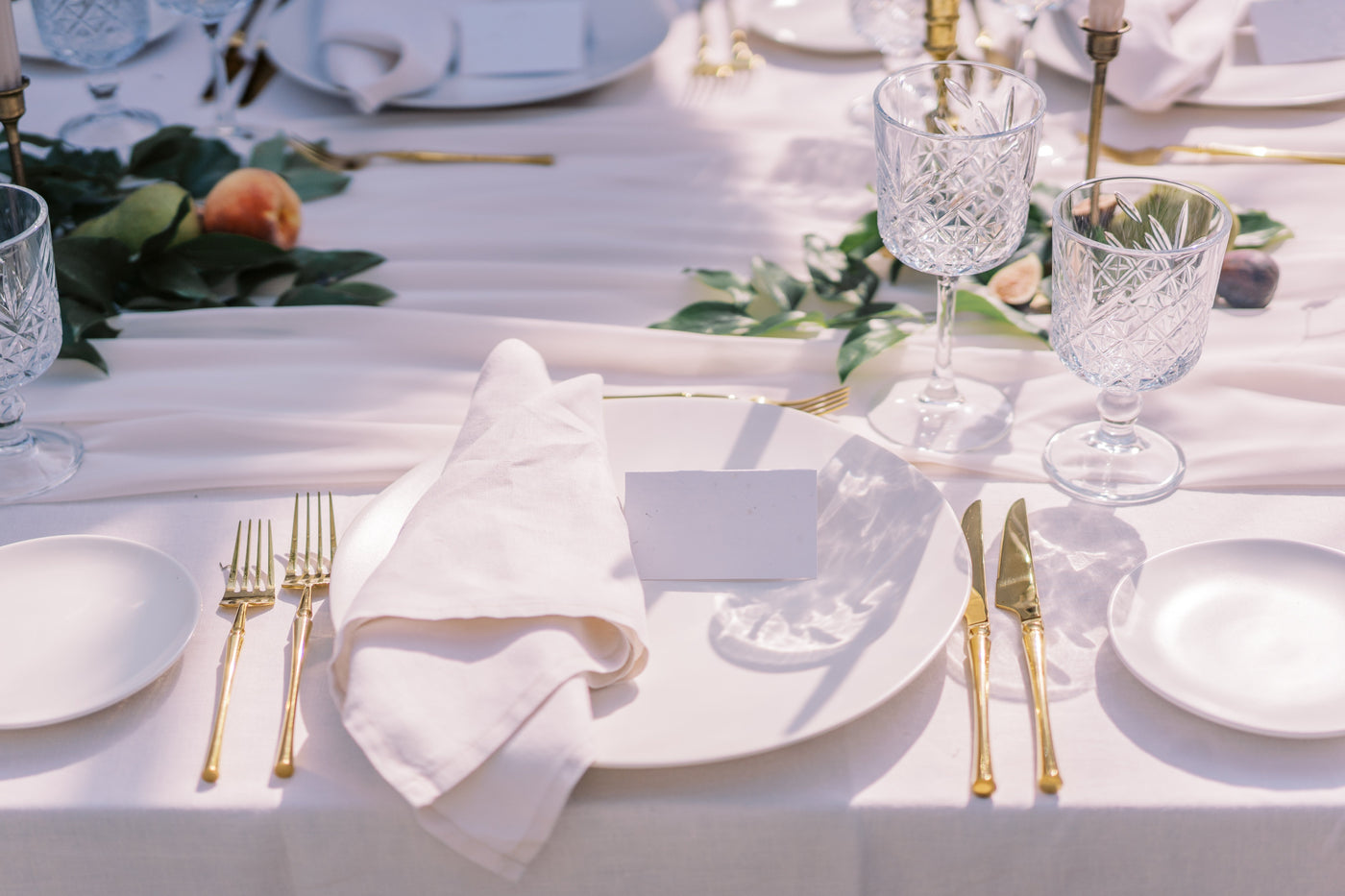 Elegant table setup, fine dining arrangement with gold cutlery, crystal glassware, and a white napkin.